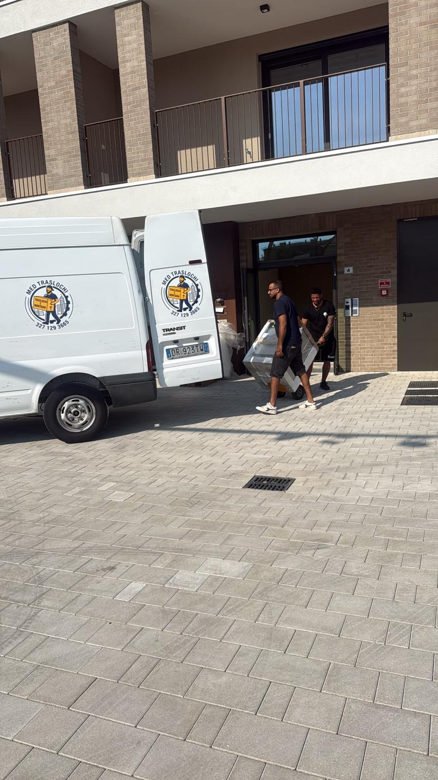 Il team MED Traslochi scarica un mobile dal furgone durante un trasloco a Giussano, Monza-Brianza